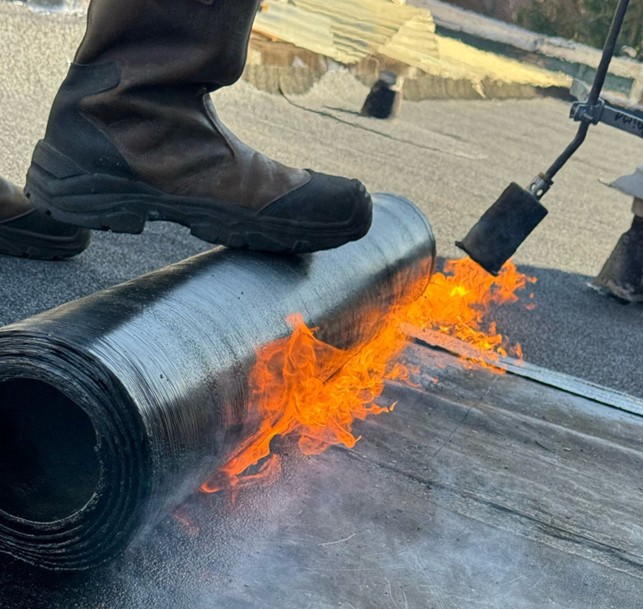 Werken op het dak met de brander en nieuw dakleer aanbrengen